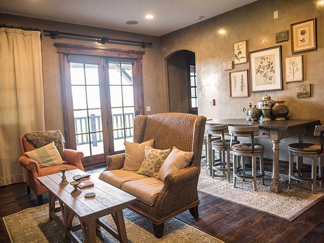 Angle shot of living area showing stuffed chairs and coffee table, with dining table and chairs in background