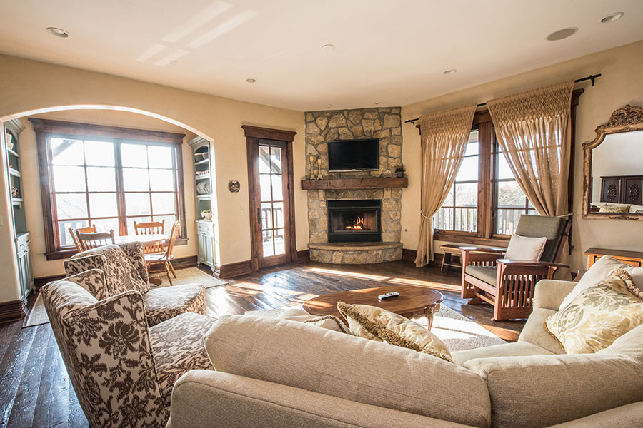 Living area with couch, stuffed chairs, large windows, stone fireplace and TV